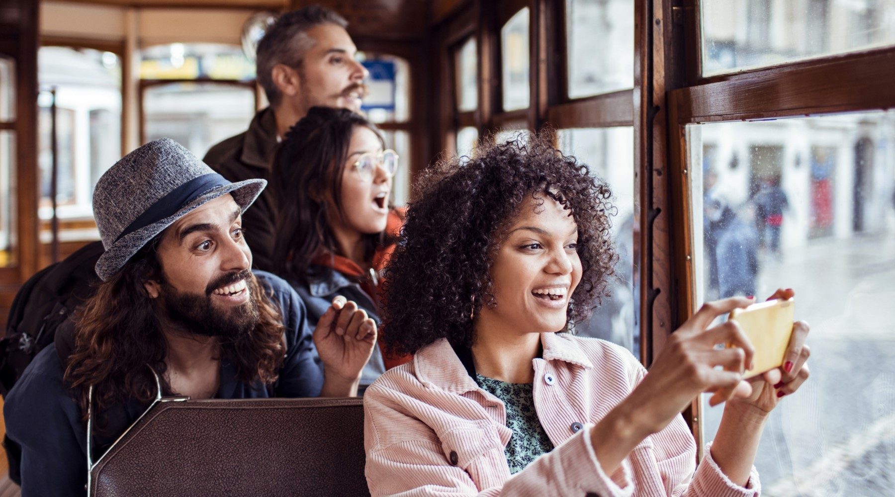 Four travelers on a tram, sightseeing and taking photographs