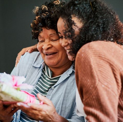 shot of a young woman giving her elderly relative a present on the sofa at home