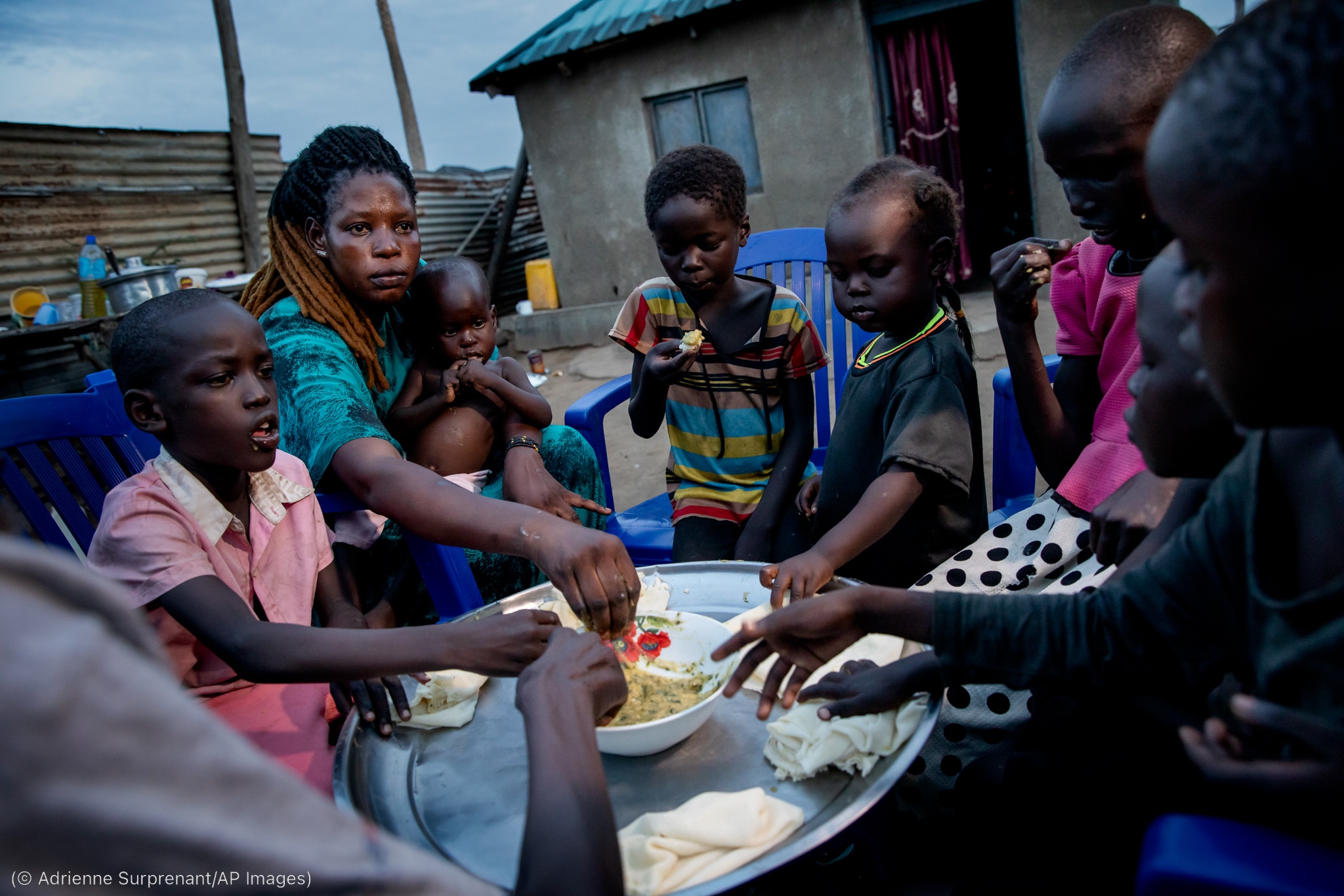 Woman and children sharing bowl of food (© Adrienne Surprenant/AP Images)